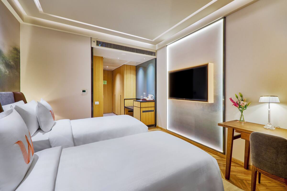 Une chambre d’hôtel avec deux lits, une télévision, un bureau et une chaise.