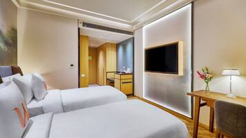 Une chambre d’hôtel avec deux lits, une télévision, un bureau et une chaise.