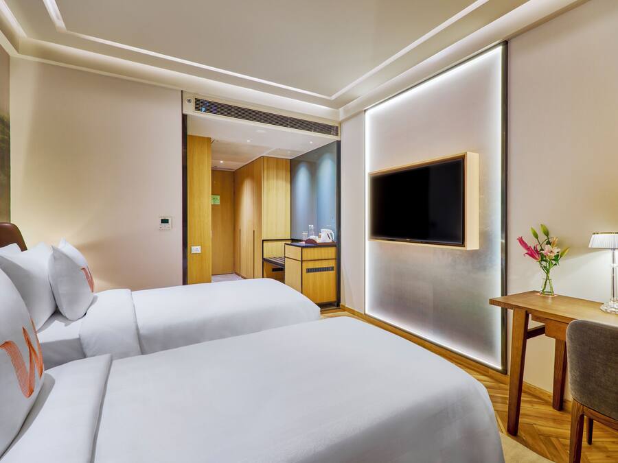 Une chambre d’hôtel avec deux lits, une télévision, un bureau et une chaise.