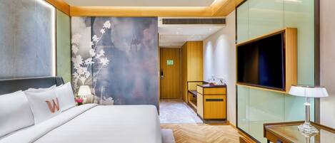 A hotel room with a bed, a desk, a TV, and a wall with a floral design.