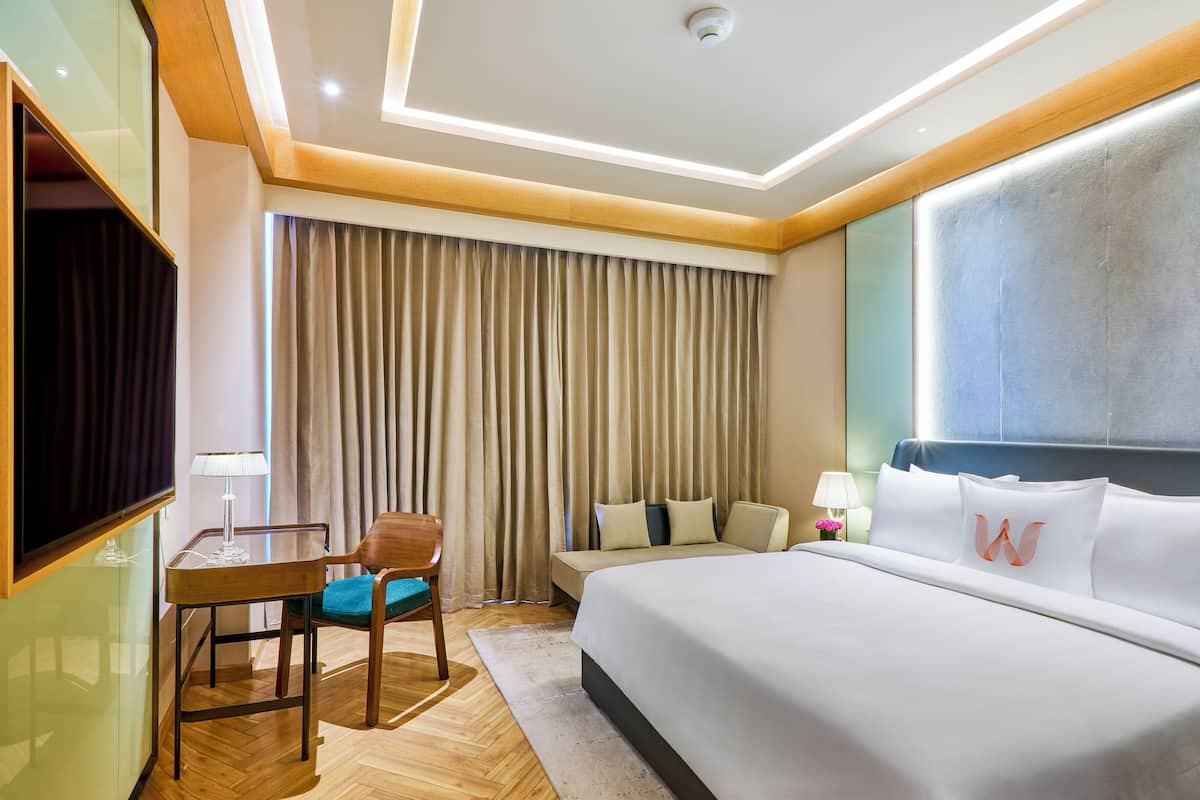 Une chambre d’hôtel équipée d’un lit, d’un bureau, d’une chaise, d’une télévision et d’une fenêtre avec des rideaux.