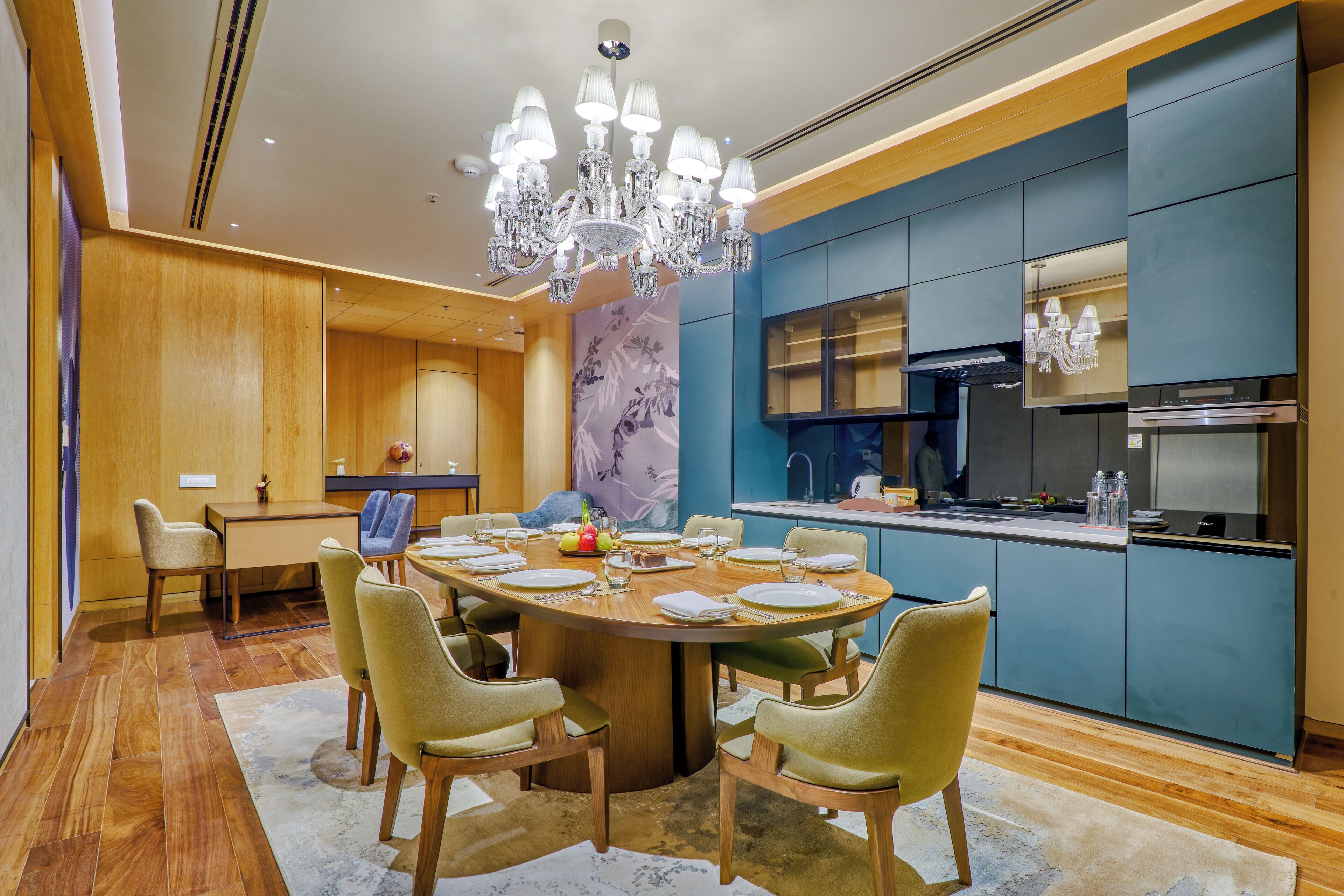 A modern dining area with a round table, chairs, and a chandelier.