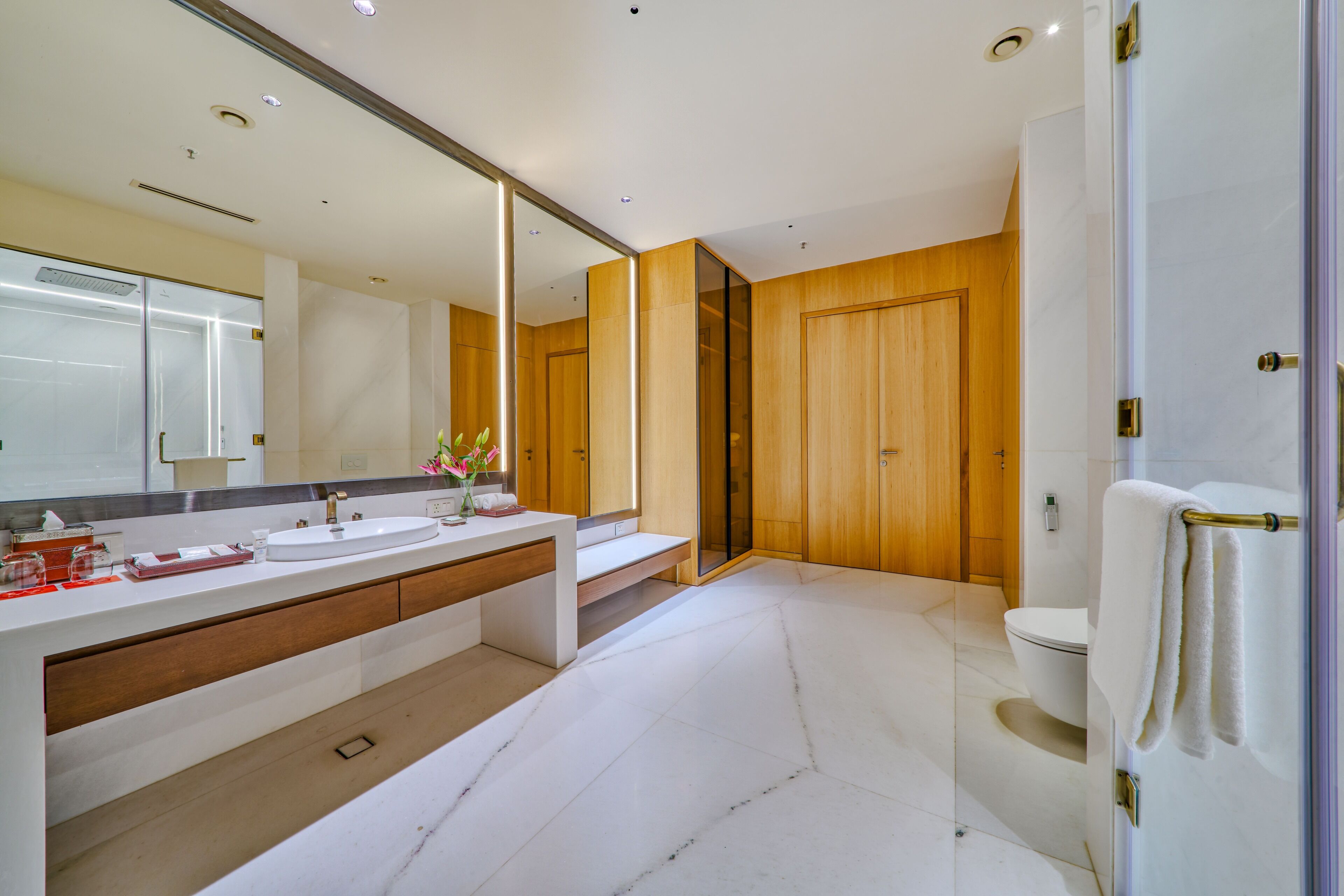 Une salle de bain moderne avec un grand miroir, un lavabo et des toilettes.