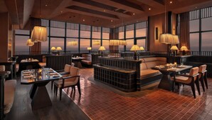 Un restaurante moderno con techos altos, ventanas amplias y diversas opciones de asientos, incluyendo mesas y cabinas.