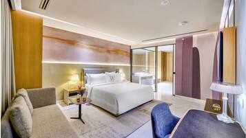 A modern hotel room with a bed, a sofa, a desk, and a chair.