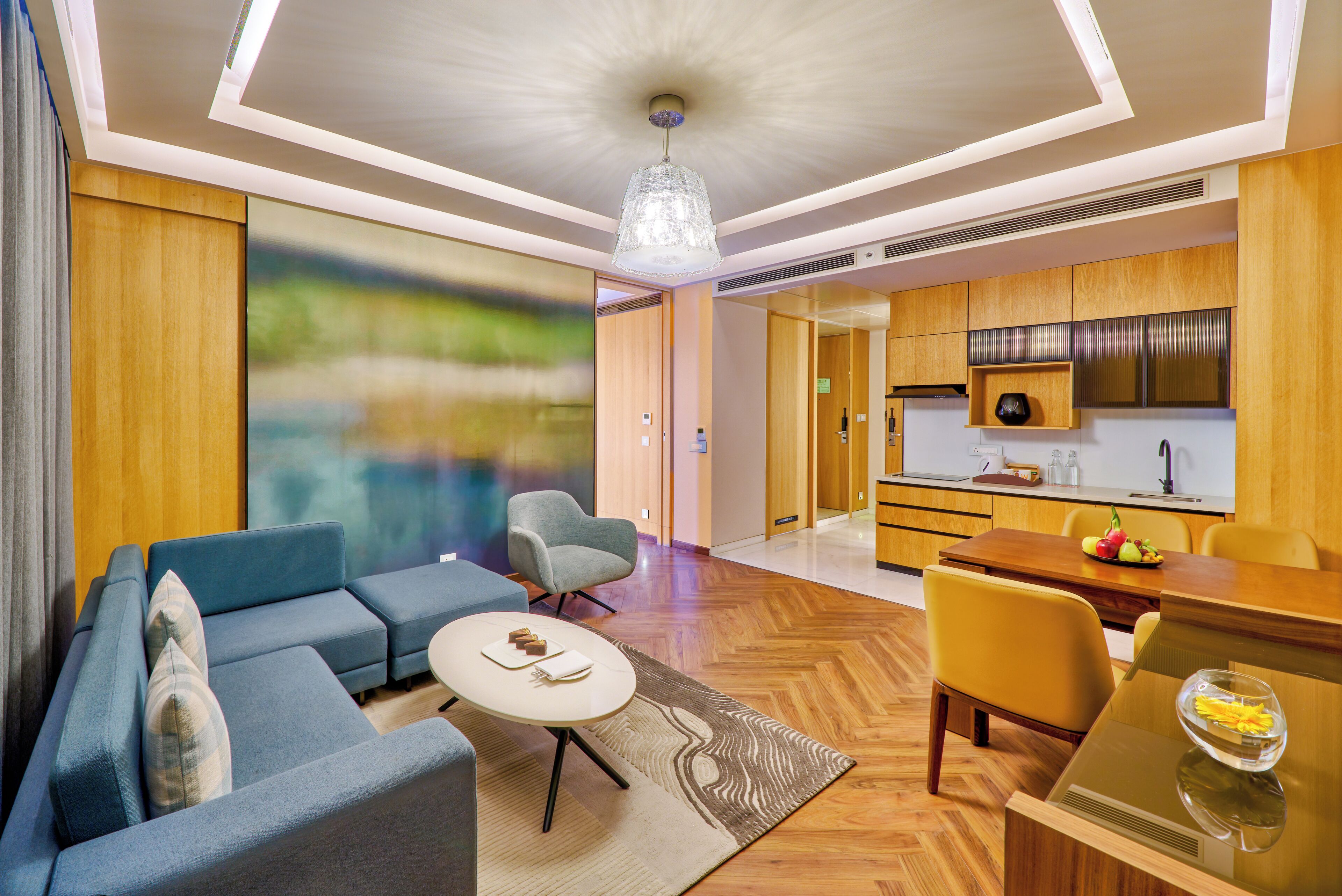A modern living room with a sofa, chairs, a dining table, and a kitchen area.