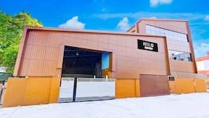 A modern hotel with a large open entrance, a sign indicating it's a hotel, and a clear blue sky in the background. - Hotel O Kundrathur Near Murugan (Chennai)