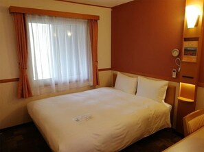 A hotel room with a large bed, a window with curtains, a bedside table with a lamp, and a wall clock. - Toyoko Inn Tokyo Yamanote-sen Otsuka-eki Kita-guchi No.2 (Tokyo)