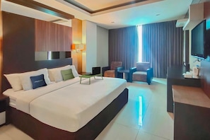 A modern hotel room with a large bed, a desk, a chair, and a TV. - Urbanview Hotel Newton Riau Bandung (Bandung)