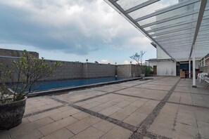 A rooftop pool area with a glass enclosure, a concrete wall, and a potted plant. - Urbanview Hotel Newton Riau Bandung (Bandung)
