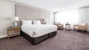 Habitación de hotel con una cama grande, dos mesitas de noche, una lámpara y una silla.