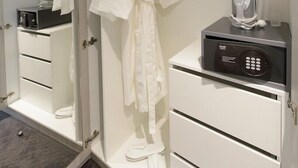 A hotel room with a walk-in closet containing a robe, a set of drawers, and a mirror. There is a hairdryer and an iron on the counter. - Miramare Gardens Boutique Accommodation (Sydney)