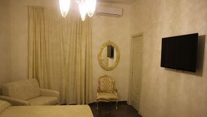 Una habitación de hotel con una cama, una silla, un televisor y un espejo.