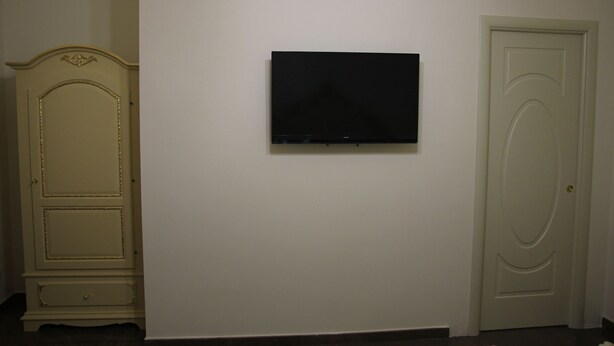 Una habitación con una televisión de pantalla plana montada en la pared, una puerta blanca y un armario de madera.