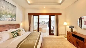 Un dormitorio con una cama grande, cabecera de madera, un cuadro, un espejo y vistas a la cocina y al salón a través de una puerta de cristal.