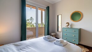 A bedroom with a bed, a dresser, a mirror, and a balcony with curtains. - GuestReady - Nature and tranquillity in Madeira (Gaula)