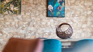 A stone wall with a framed painting of a parrot and a woven basket on a wooden table. - GuestReady - Nature and tranquillity in Madeira (Gaula)