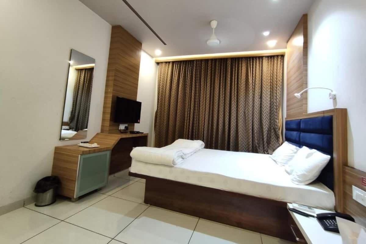A modern hotel room with a bed, a desk, a television, and a mirror.