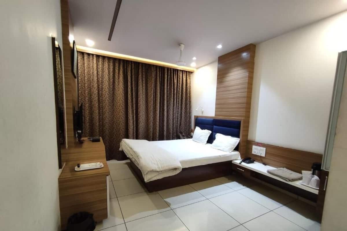 A modern hotel room with a large bed, a bedside table, a mirror, and a curtain.
