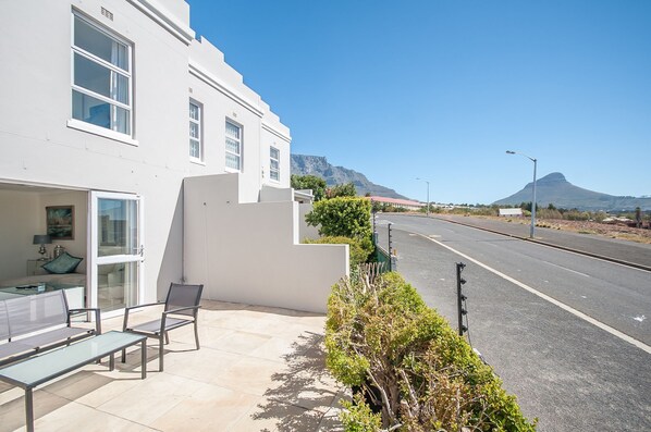 A modern building with a patio area featuring a glass door, a bench, and a small table. - 3 Canterbury Square (Cape Town)