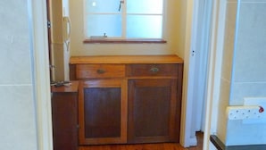 A narrow kitchen with wooden cabinets, a window with frosted glass, and a light fixture above. - Bramber Court (Cape Town)