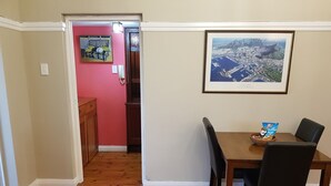 A dining area with a wooden table and chairs, a framed cityscape picture, and a red rug. - Bramber Court (Cape Town)
