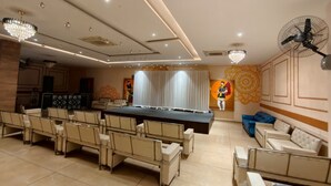 Une salle de conférence avec une longue table, des chaises, une scène et un ventilateur.