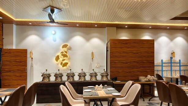 Un espace de salle à manger moderne, avec une table centrale entourée de chaises et un mur décoratif agrémenté d’un luminaire original.