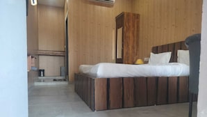 Une chambre avec un lit en bois, une petite table de chevet, une lampe et une armoire en bois.