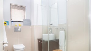 A bathroom with a toilet, sink, and shower area. - 236 Eden On the Bay (Cape Town)