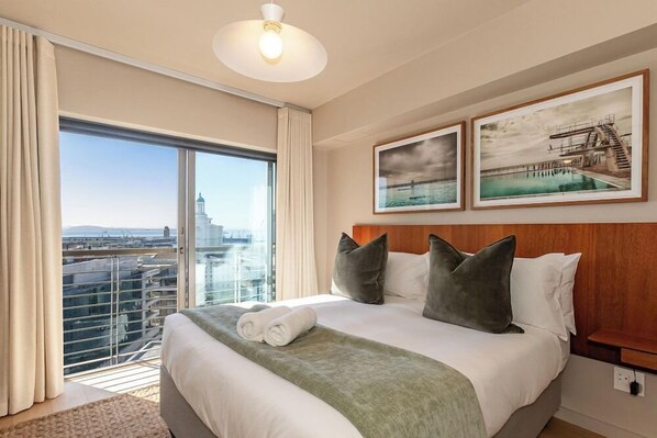 A hotel room with a large bed, a view of the city, and two framed pictures on the wall. - The Icon by ITC Hospitality (Cape Town)