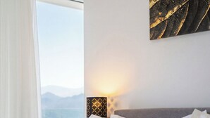 Hotellihuone, jossa on sänky, merinäköala ja seinään kiinnitetty valaisin.