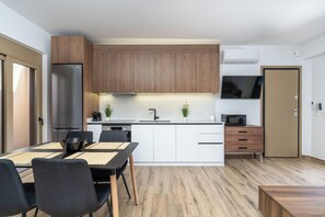 Eine moderne Küche mit Holzschränken, einem Edelstahlkühlschrank, einer Mikrowelle und einem Essbereich mit Tisch und Stühlen.