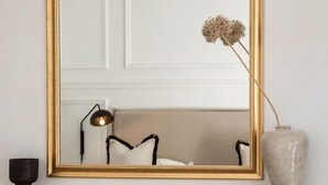 A fireplace with a gold-framed mirror above it, a vase with dried flowers, and a lamp on the mantel. - Underberg House (Cape Town)