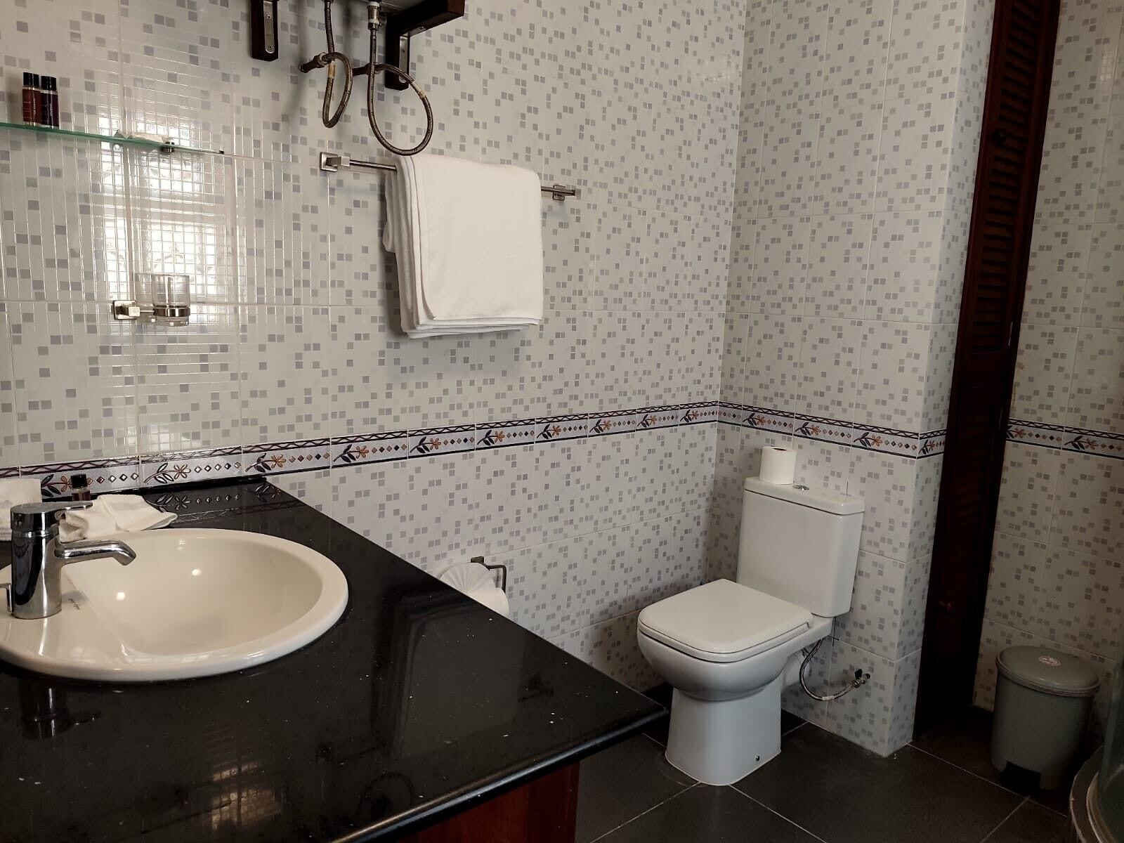 A bathroom with a white sink, black countertop, and a toilet.
