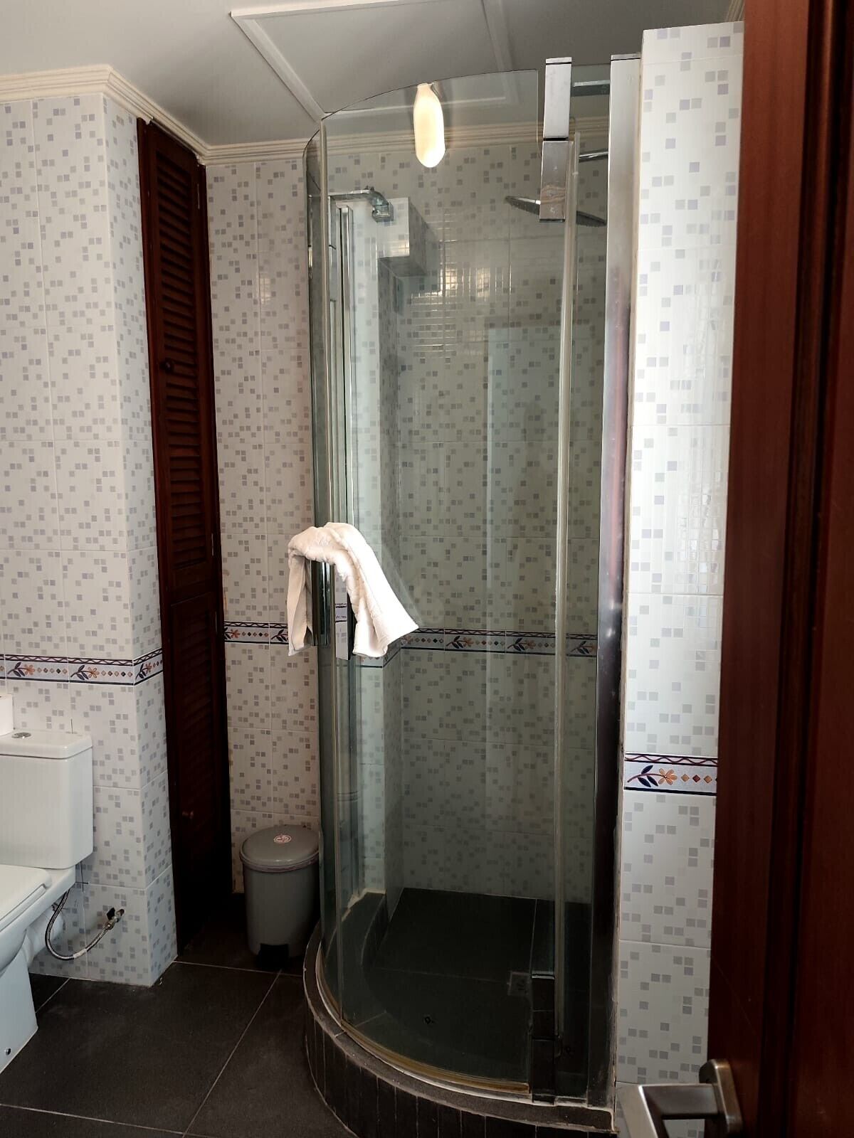 A bathroom with a glass-enclosed shower, a toilet, and a sink.