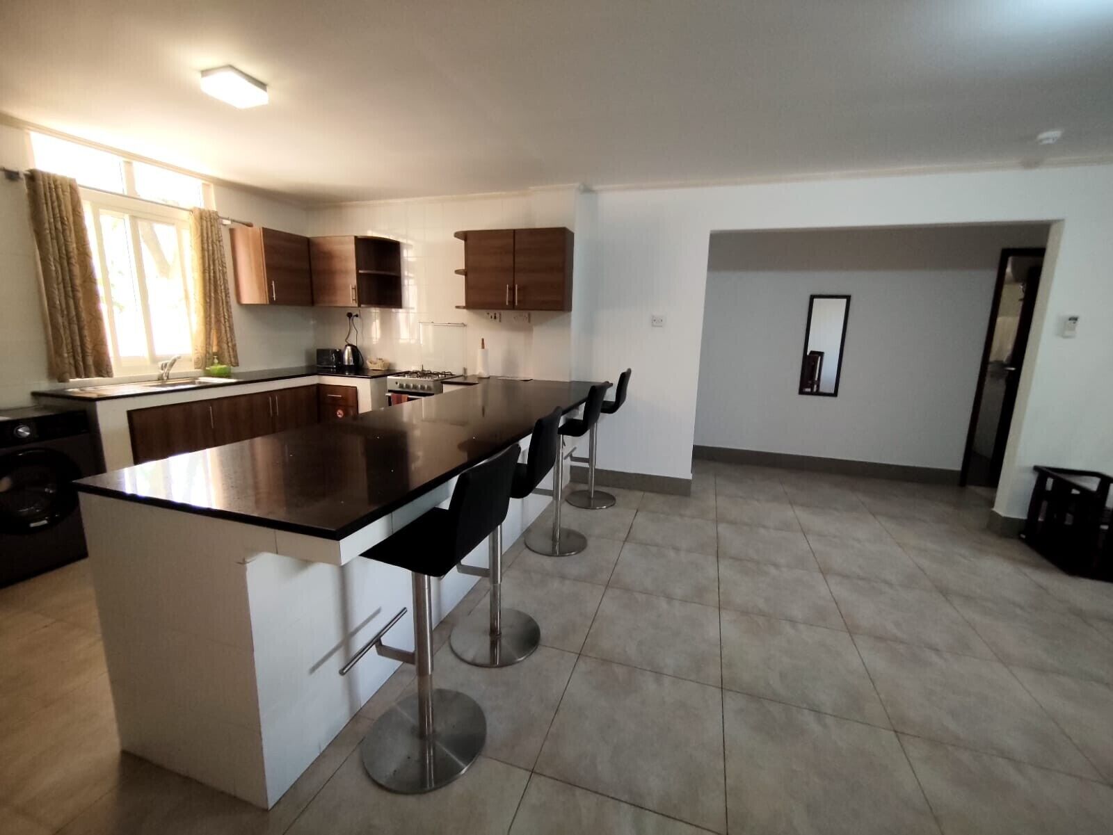 Una cucina moderna con isola centrale, sgabelli da bar e zona pranzo.