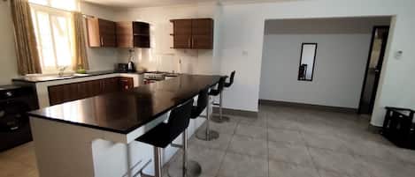 Una cocina moderna con una isla central, taburetes de bar y una zona de comedor.