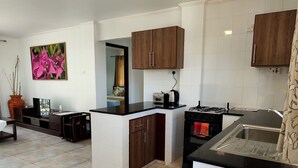 Una cocina moderna con azulejos blancos, armarios de madera, encimera negra y estufa a gas.
