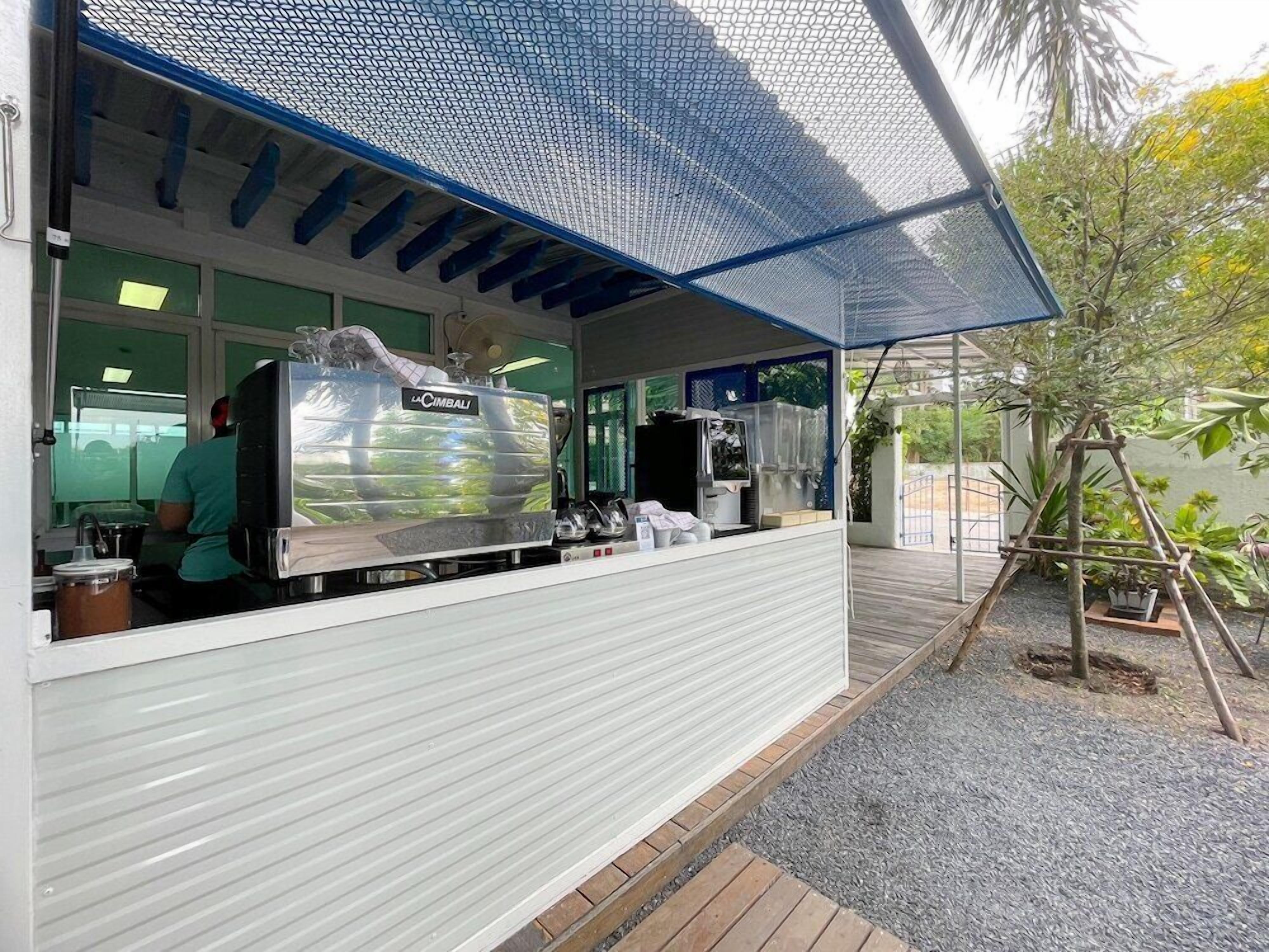A food kiosk with a La Cimbali espresso machine, a counter, and a person behind it.