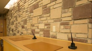 Un espace d’accueil avec un mur en pierre et deux comptoirs dotés de plaques nominatives.