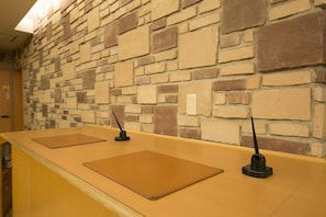 Un espace d’accueil avec un mur en pierre et deux comptoirs dotés de plaques nominatives.