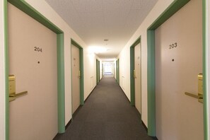 A hotel hallway with doors numbered 204 and 203, featuring green door frames and gold handles. - R B Hotel Kyoto Eki Hachijoguchi (Kyoto)