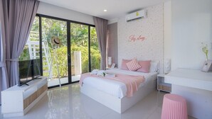 Un dormitorio moderno con una cama grande, un escritorio y vistas a la vegetación exterior.