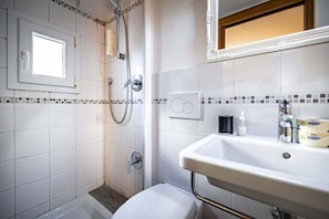 Ein Badezimmer mit Dusche, Toilette, Waschbecken und Spiegel.