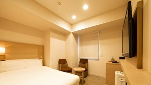 A hotel room with a bed, two chairs, a small table, a TV, and a window with blinds. - Viainn Higashi Ginza (Tokyo)