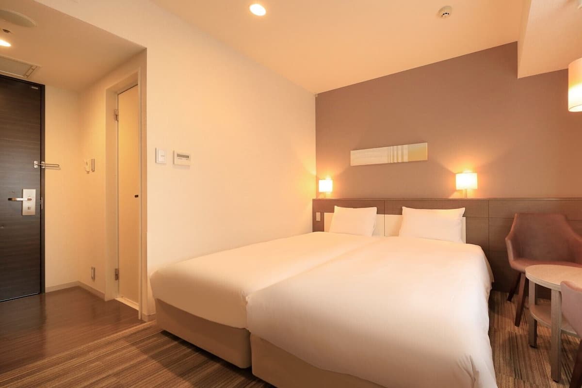 Ein Hotelzimmer mit einem großen Bett, Nachttischen, einem Sessel und einem Schreibtisch.