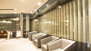 A modern hotel lobby with a seating area, a reception desk, and a glass partition with vertical lines. - Viainn Higashi Ginza (Tokyo)