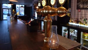 Una zona de bar con varias llaves de cerveza y una botella de licor en la barra.