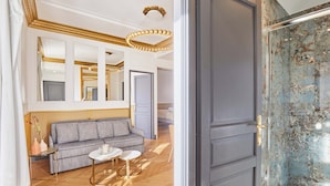 Et moderne hotelværelse med sofa, rundt bord og stort spejl.